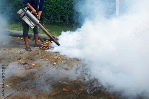 Staff are injecting chemicals to get rid of the mosquitoes in the drain. Asian men are spraying smoke to destroy the origin of dengue fever.
