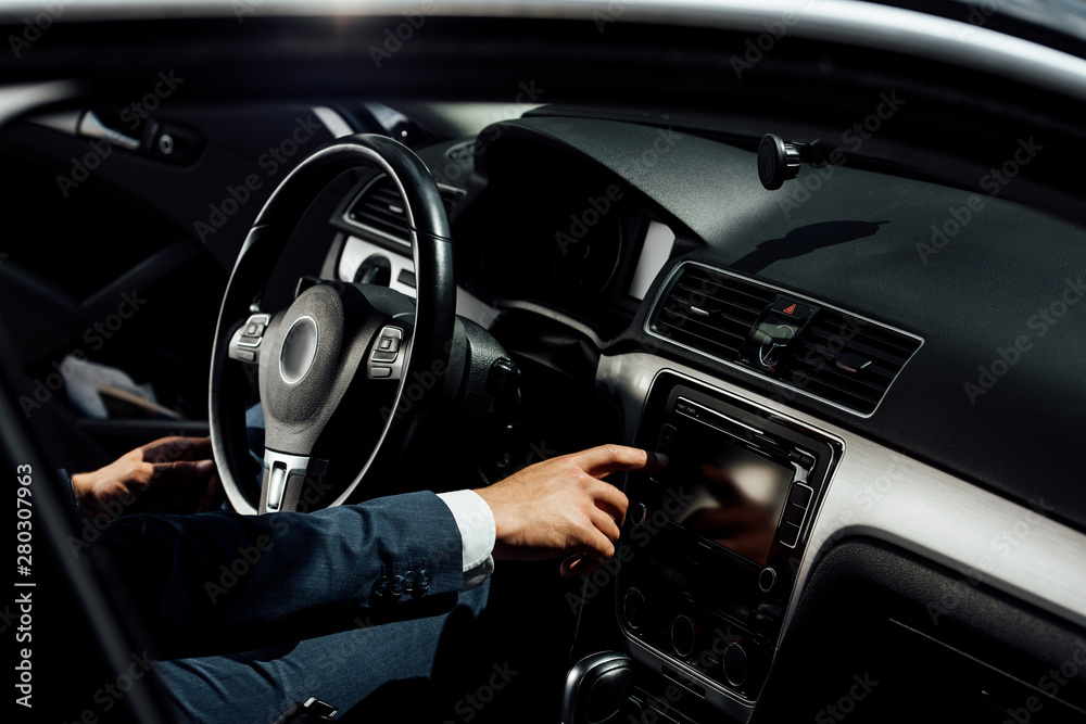 cropped view of african american businessman in suit pushing button in car