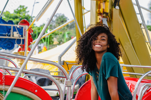 young girl of black color, laughing hair in ferris wheel, sitting enjoying a summer day, lifestyle portrait