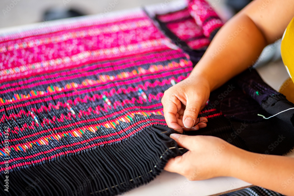 Close up hands using needle sewing Hmong skirt