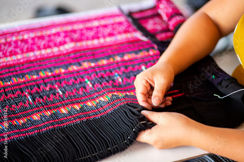 Close up hands using needle sewing Hmong skirt