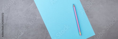 Flat lay, top view, blue sheet and pencil on a gray textured background.