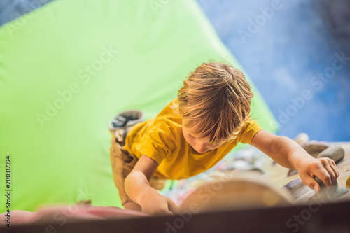 little boy climbing a rock wall in special boots. indoor