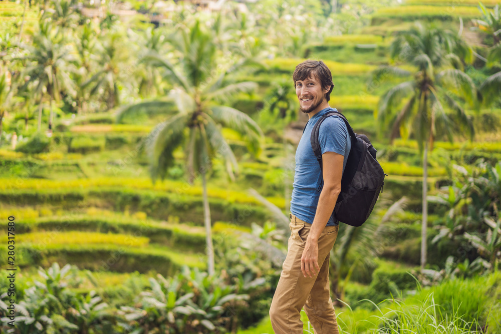 Male tourist with a backpack goes on the rice field Male tourist with a backpack goes on the rice field