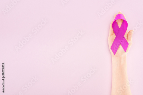 cropped view of purple ribbon on hand of woman isolated on pink