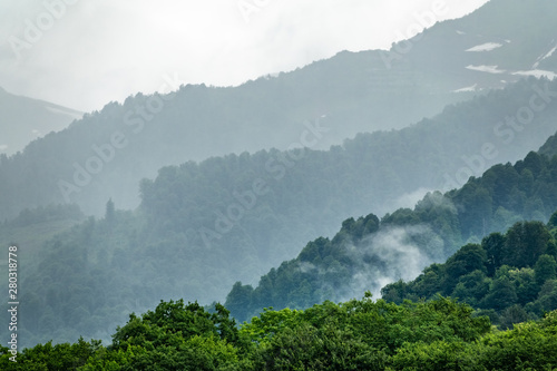 High mountains with forested slopes and peaks hidden in the clouds.