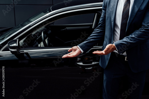 cropped view of african american man in suit pointing at black car door © LIGHTFIELD STUDIOS