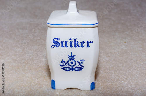Delft Blue Sugar (Suiker) container. Famous porcelain souvenirs from Holland/Netherlands. Isolated on textured beige background.