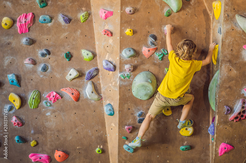 little boy climbing a rock wall in special boots. indoor