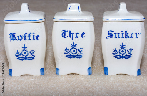 Delft Blue Coffee, Tea, and Sugar (Koffie, Thee, Suiker) containers. Famous porcelain souvenirs from Holland/Netherlands. Isolated on textured beige background. photo