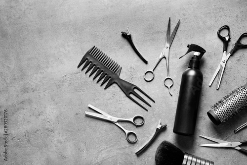Flat lay composition with scissors and other hairdresser's accessories on grey background. Space for text