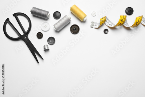 Composition with scissors and other sewing accessories on white background, top view