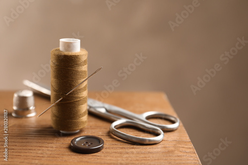 Scissors and other sewing accessories on wooden table, space for text