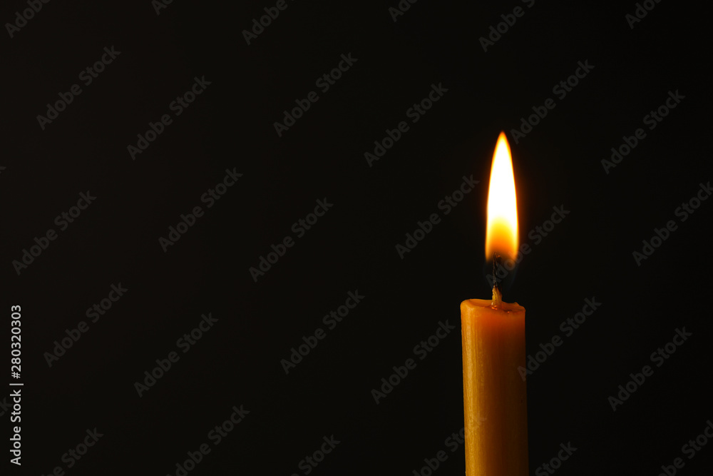 Burning candle on dark background, space for text. Symbol of sorrow Burning candle on dark background, space for text. Symbol of sorrow