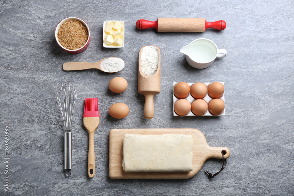 Flat lay composition with puff pastry dough and ingredients on grey table Flat lay composition with puff pastry dough and ingredients on grey table