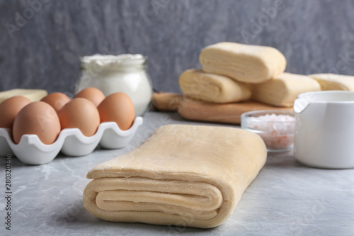 Raw puff pastry dough and ingredients on grey table
