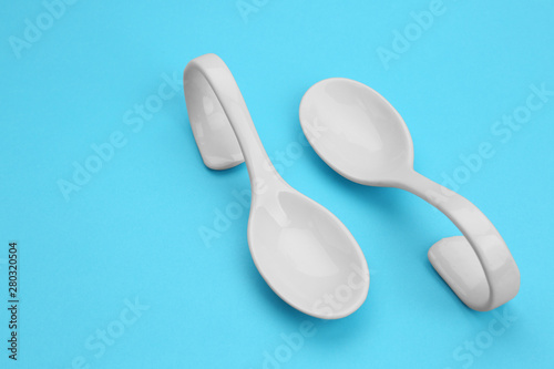 Clean empty ceramic appetizer spoons on blue background, space for text