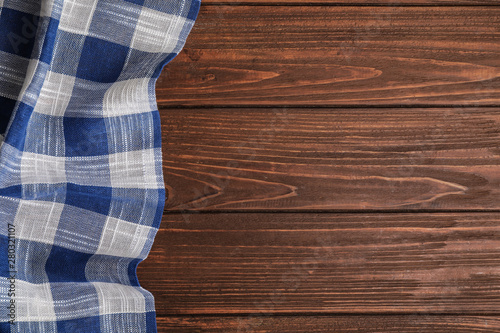 Blue plaid kitchen towel on wooden background, top view. Space for text