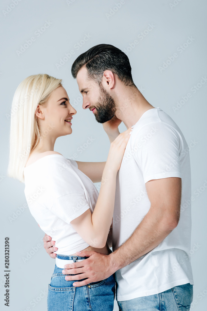 beautiful happy young couple embracing and smiling isolated on grey