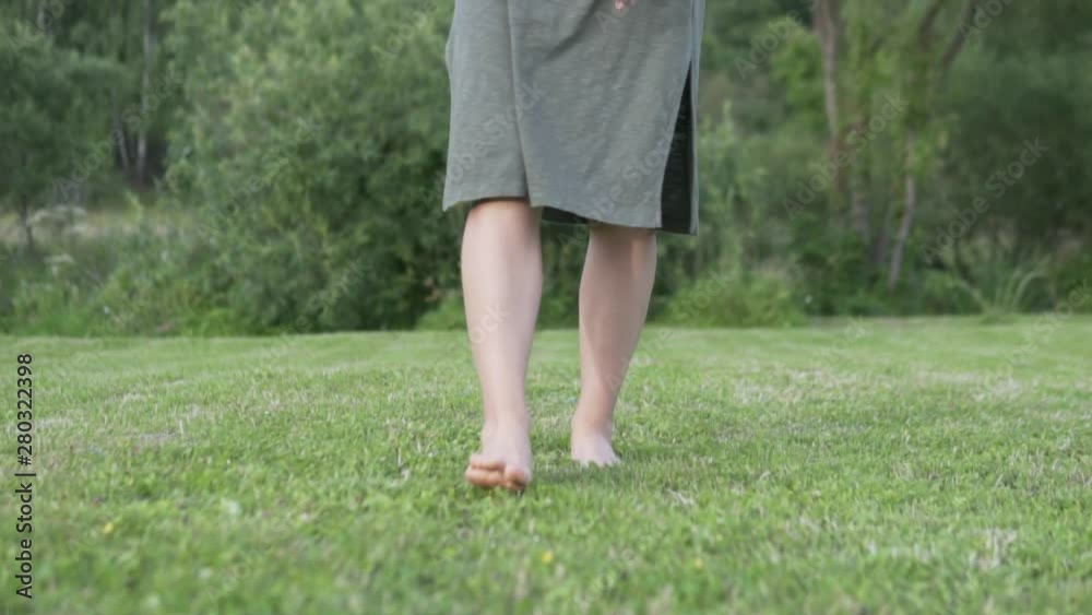 Female legs walking slowly through the green grass in the morning Female legs walking slowly through the green grass in the morning