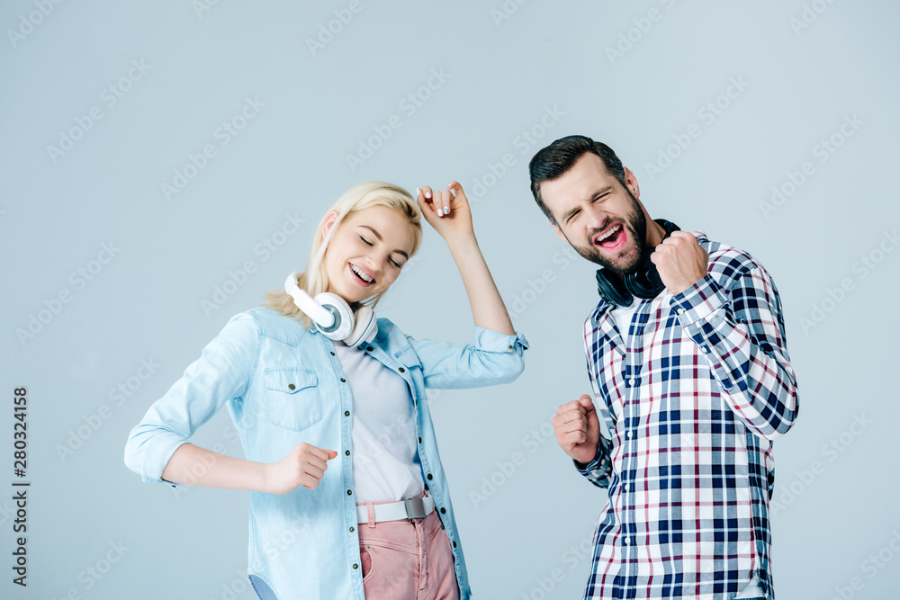 happy man and girl with headphones dancing isolated on grey happy man and girl with headphones dancing isolated on grey
