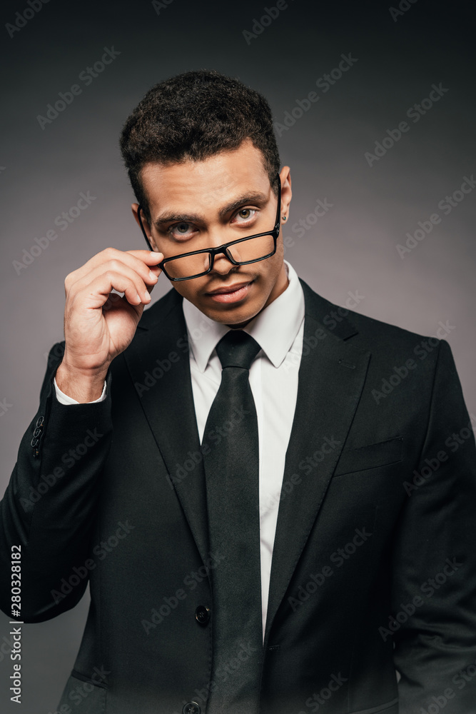 handsome african american businessman in glasses and suit on dark background handsome african american businessman in glasses and suit on dark background