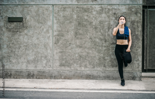 An beautiful Asian woman running and listening music over road during moring. Workout and sport outdoor concept.