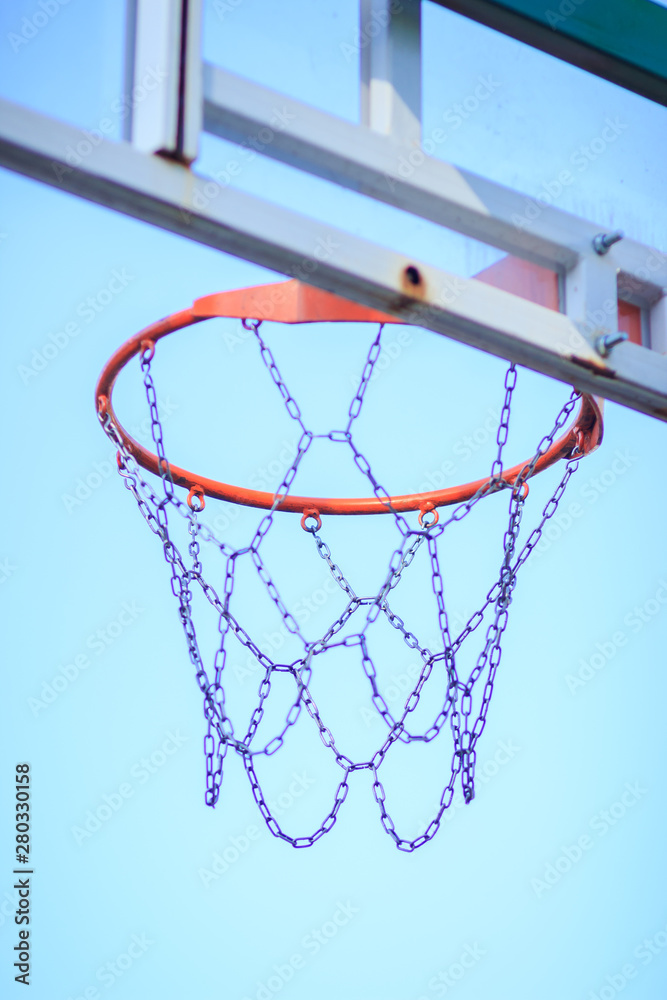Netted hoop for basketball game on the blue sky background, outdoors, blurred background