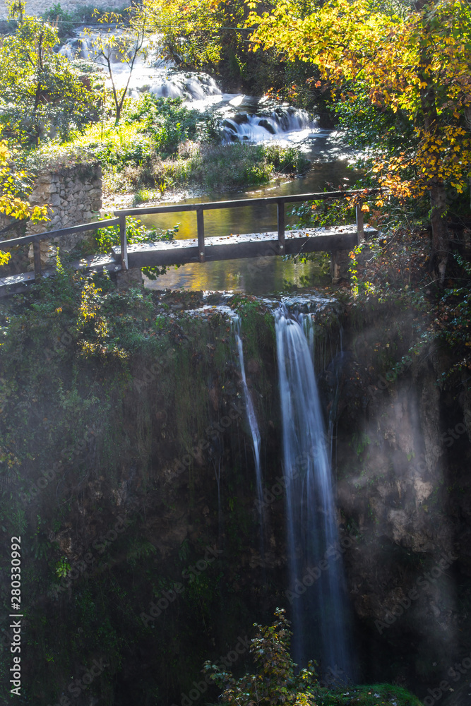 Fototapeta premium The wooden small bridge and a waterfall