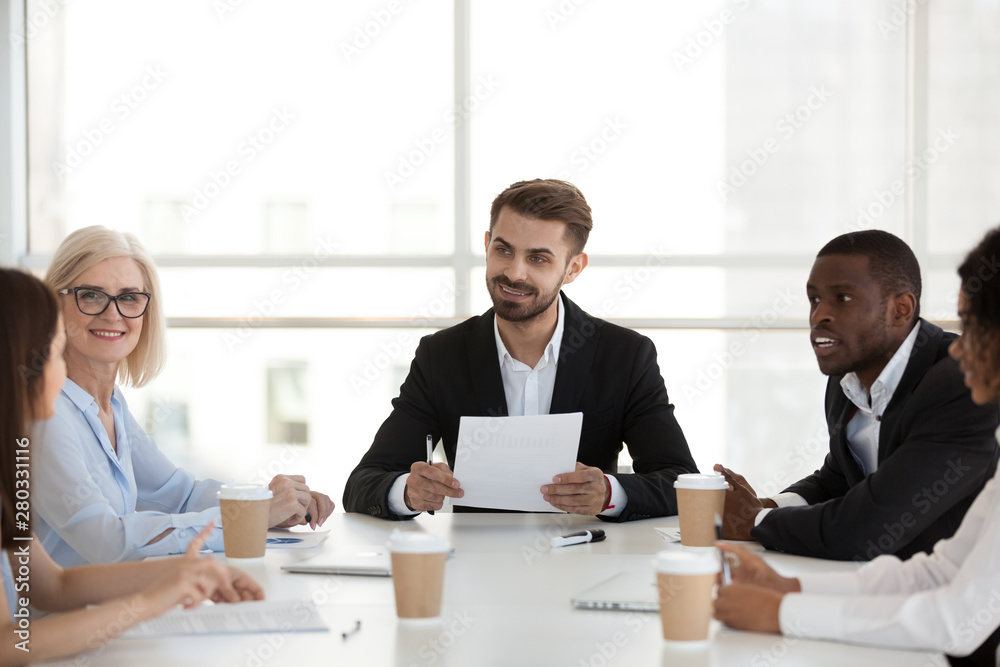 Multiethnic colleagues discuss project statistics at company meeting Multiethnic colleagues discuss project statistics at company meeting