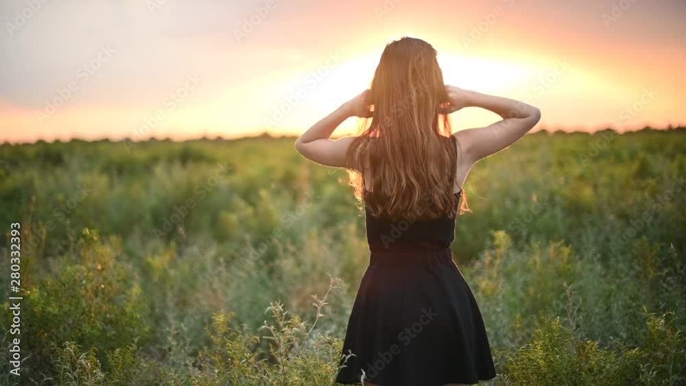 Cheerful young woman in white dress walking through beautiful lavender filed at golden sunset in summer Cheerful young woman in white dress walking through beautiful lavender filed at golden sunset in summer