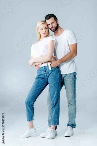 man and beautiful young woman in denim hugging on grey