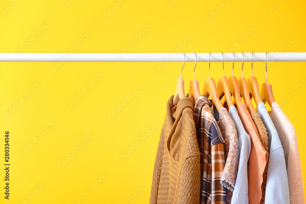 Rack with hanging clothes on color background - obrazy, fototapety, plakaty 
