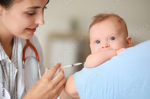 Pediatrician vaccinating little baby in clinic photo