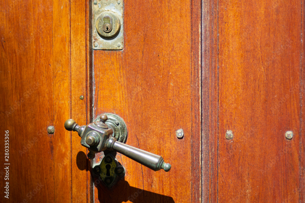 Old doorhandle on the brown door lighted by sun Old doorhandle on the brown door lighted by sun