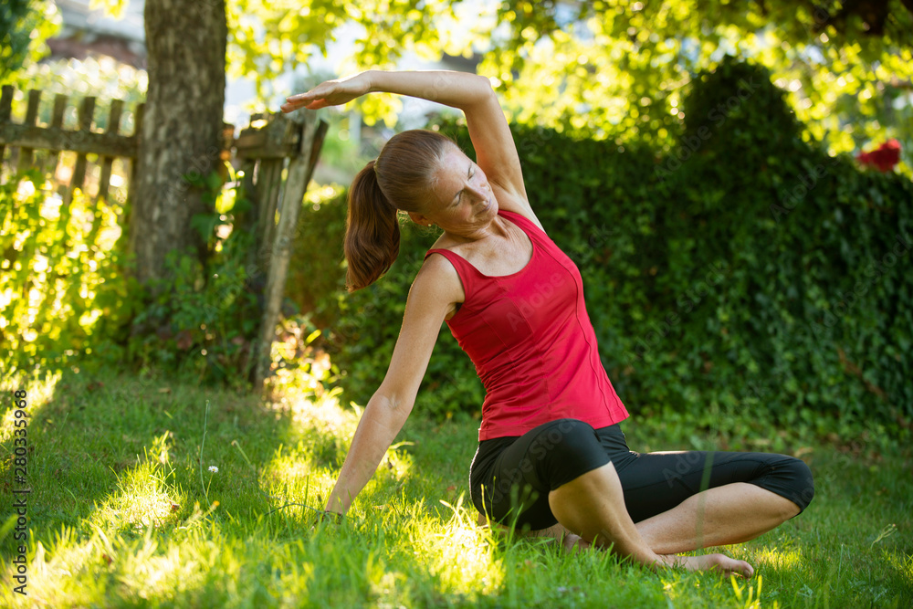 Yogaübungen im grünen Garten, Frau, erwachsen, europäisch in Sitzhaltung Yogaübungen im grünen Garten, Frau, erwachsen, europäisch in Sitzhaltung