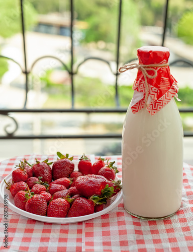 Strawberries and a glass bottle with milk.