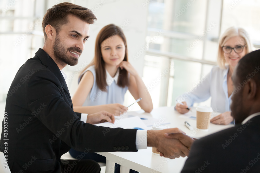 Confident businessman shaking hand colleague at company meeting Confident businessman shaking hand colleague at company meeting