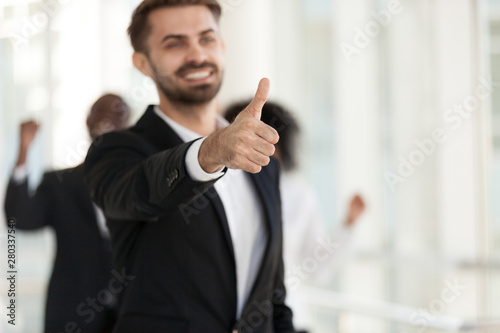 Excited smiling employee, manager show thumbs up close up
