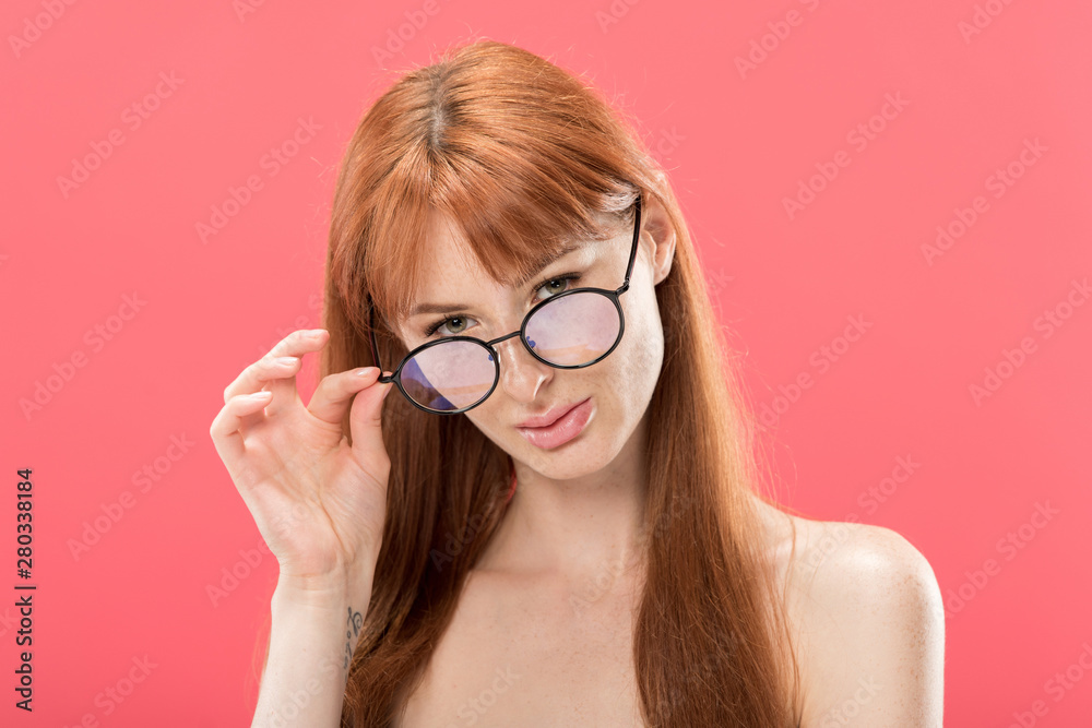 naked curious redhead woman looking at camera and touching glasses isolated on pink naked curious redhead woman looking at camera and touching glasses isolated on pink