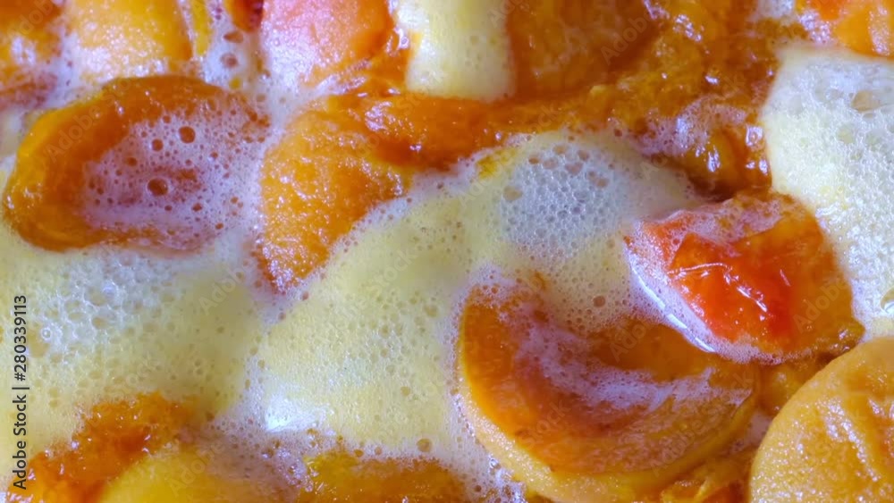 Cooking apricot jam from halves of pitted fruits in its own juice with sugar added close-up shot using camera zooming Cooking apricot jam from halves of pitted fruits in its own juice with sugar added close-up shot using camera zooming