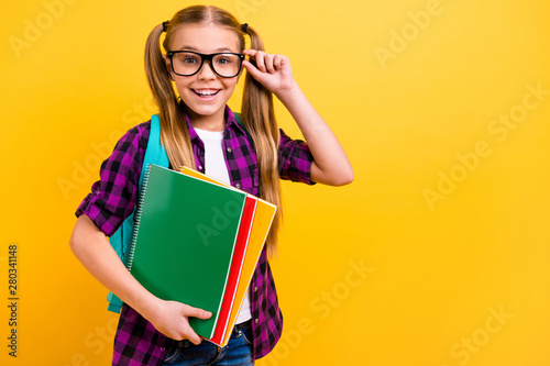 Close up photo of little lady pupil hold copybooks pretty ponytails wear specs checkered shirt isolated yellow background