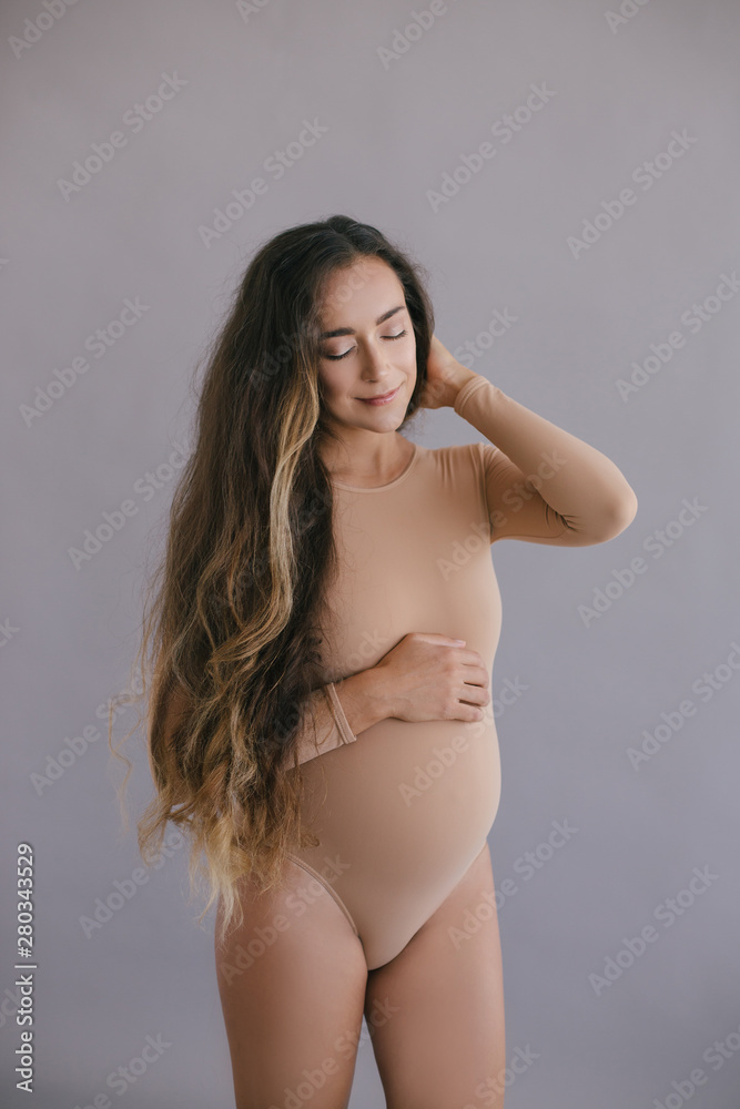 Beautiful pregnant woman with long hair on grey background Beautiful pregnant woman with long hair on grey background