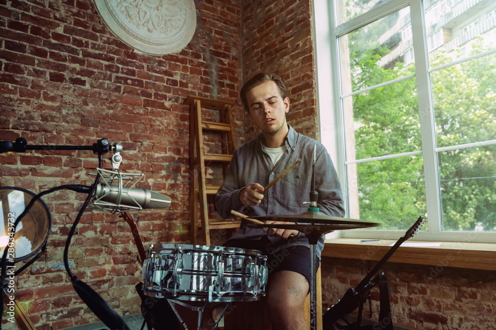 Young man recording music video blog, home lesson or song, playing drums or making broadcast internet tutorial while sitting in loft workplace or at home. Concept of hobby, music, art and creation. Young man recording music video blog, home lesson or song, playing drums or making broadcast internet tutorial while sitting in loft workplace or at home. Concept of hobby, music, art and creation.