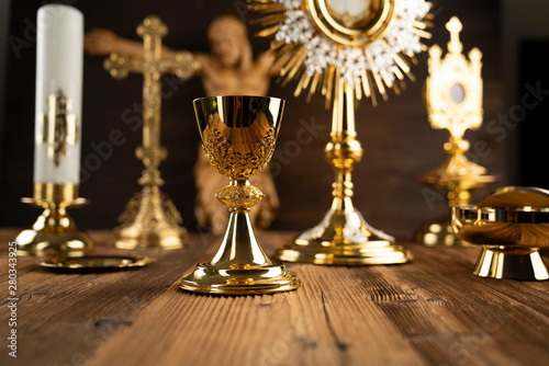 Catholic concept background. The Cross, monstrance and golden chalice on the rustic wooden altar.