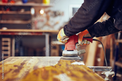 Fotografija Carpenter using orbital electric sander in a retro vintage works