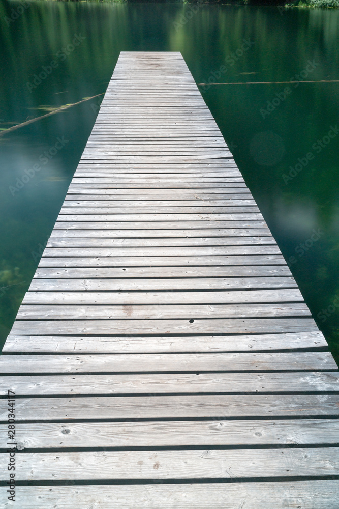 long wooden pier leads out into a mountain lake in Arosa