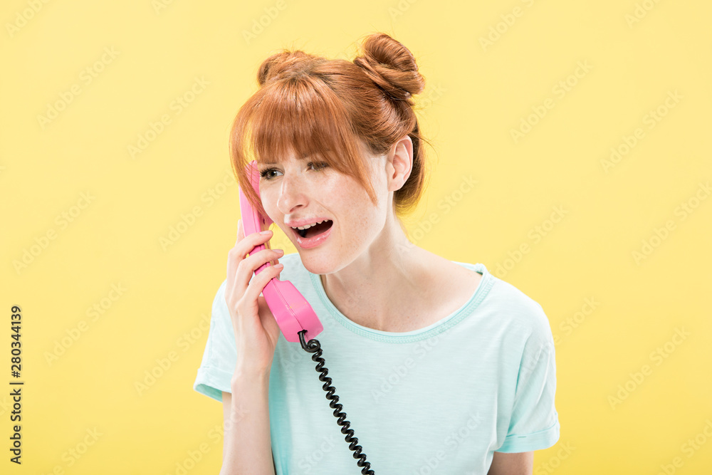 upset redhead young woman talking on retro telephone isolated on yellow upset redhead young woman talking on retro telephone isolated on yellow