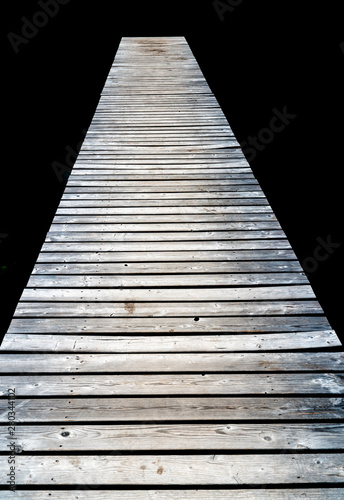 long wooden pier leads out into dark black peat lake water