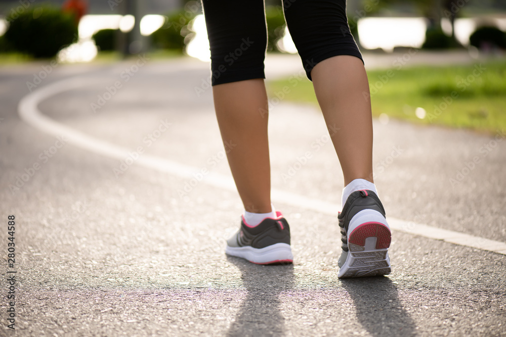 Closeup woman walking towards on the road side. Step, walk and outdoor exercise activities concept.